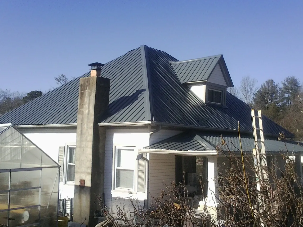 Dark blue standing seam metal roof on a white farmhouse with dormer — Slate & Tile Roof Repair by Roofing Brothers in Dingle