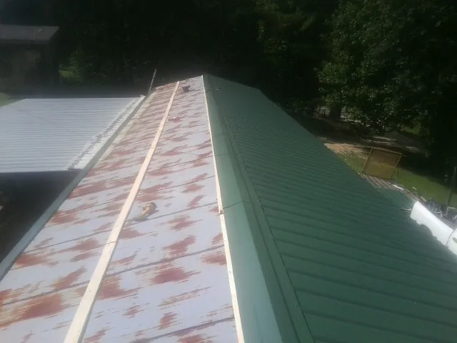 Old rusted panels beside newly installed green metal roofing — Wind Damage Roof Repair by Roofing Brothers in Dingle