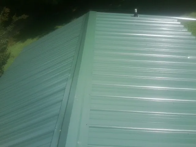 New green metal panels meeting at the ridge of a roof — Flat Roof Repair work by our crew in Dingle