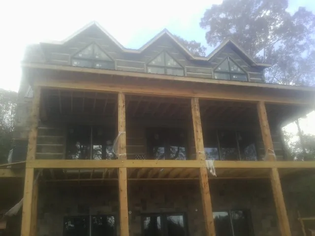 Dormers and porch framing on a large log home under construction — Roof Coating work by our crew in Dingle
