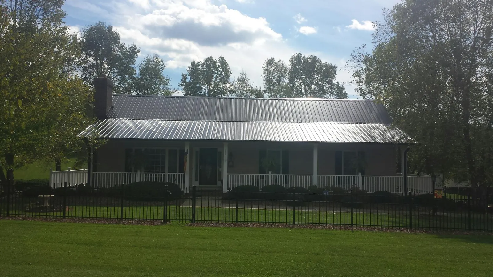 Gray metal roof on a brick ranch with a full width front porch — Gutter Guard Installation work by our crew in Dingle