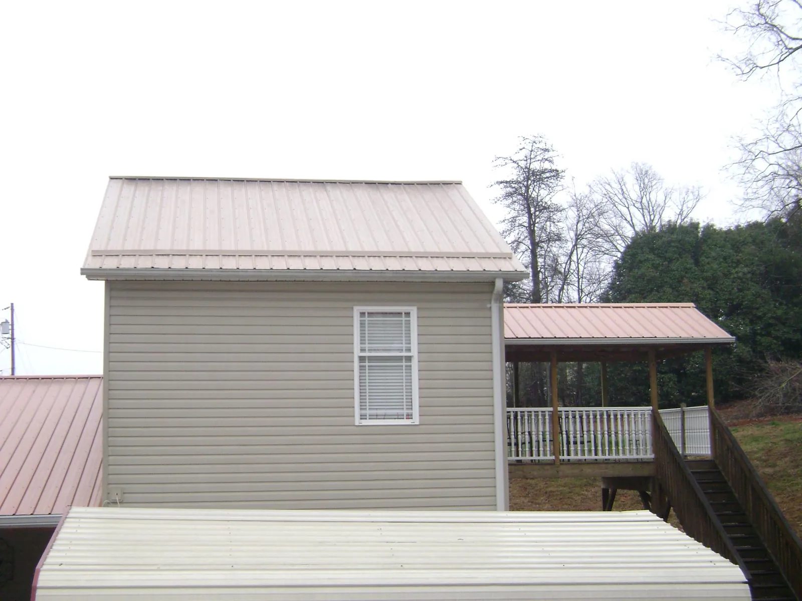 Tan metal roofs on a two story addition and attached porch, from a Roof Replacement job in Dingle